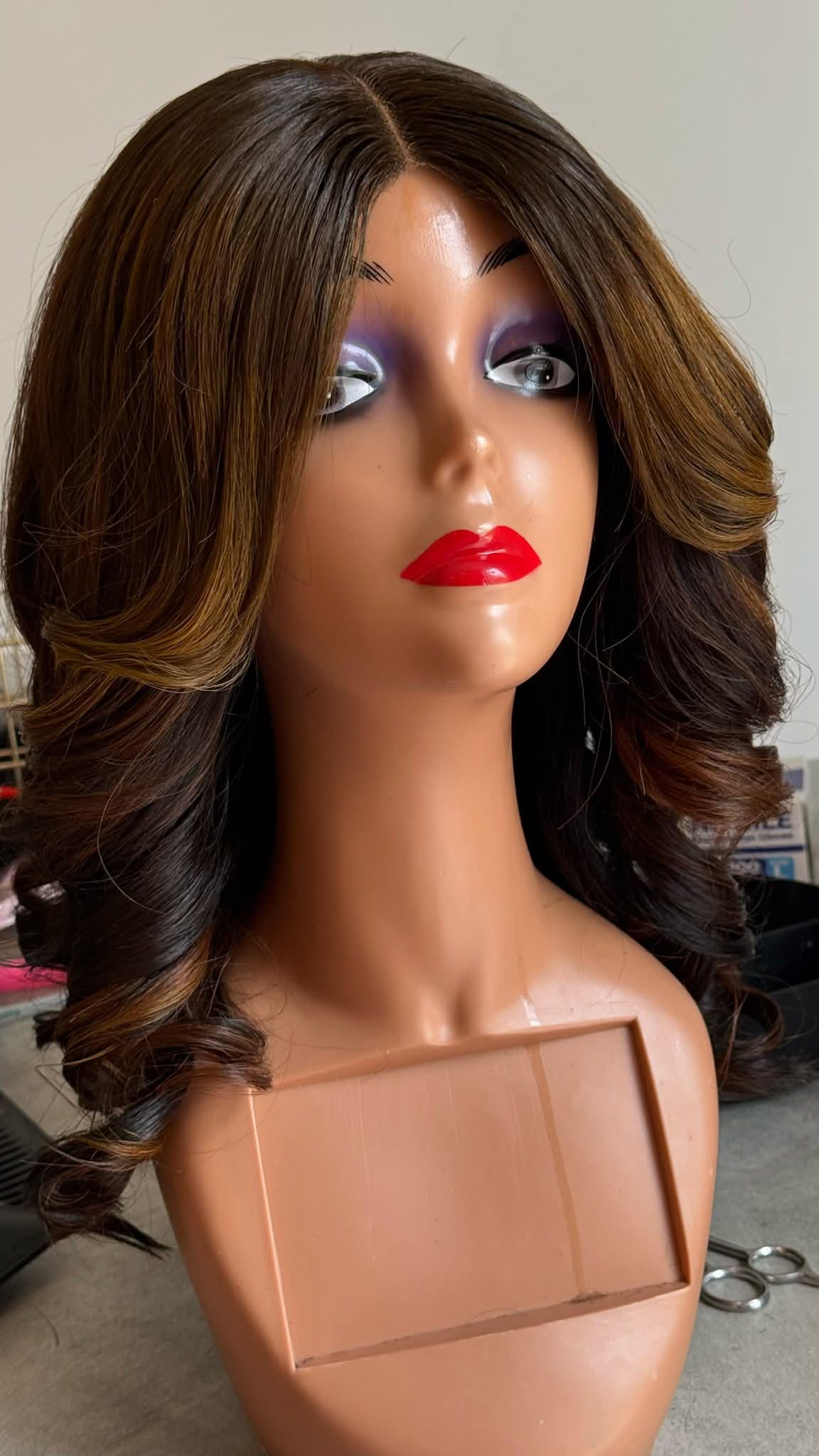 Mannequin head with a brown wig on a plain background