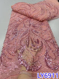 Pink embroidered fabric with intricate patterns on a plain background