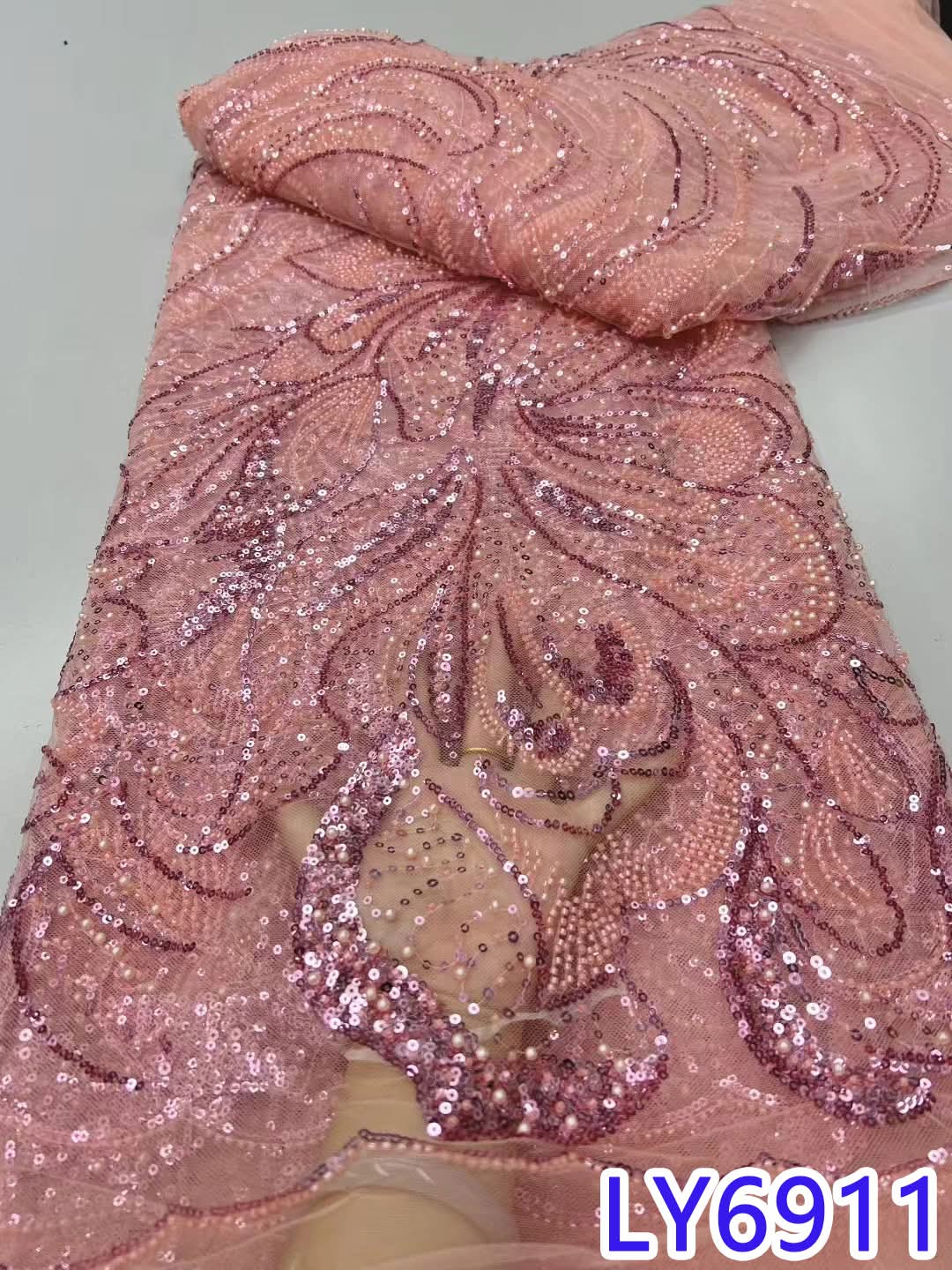 Pink embroidered fabric with intricate patterns on a plain background