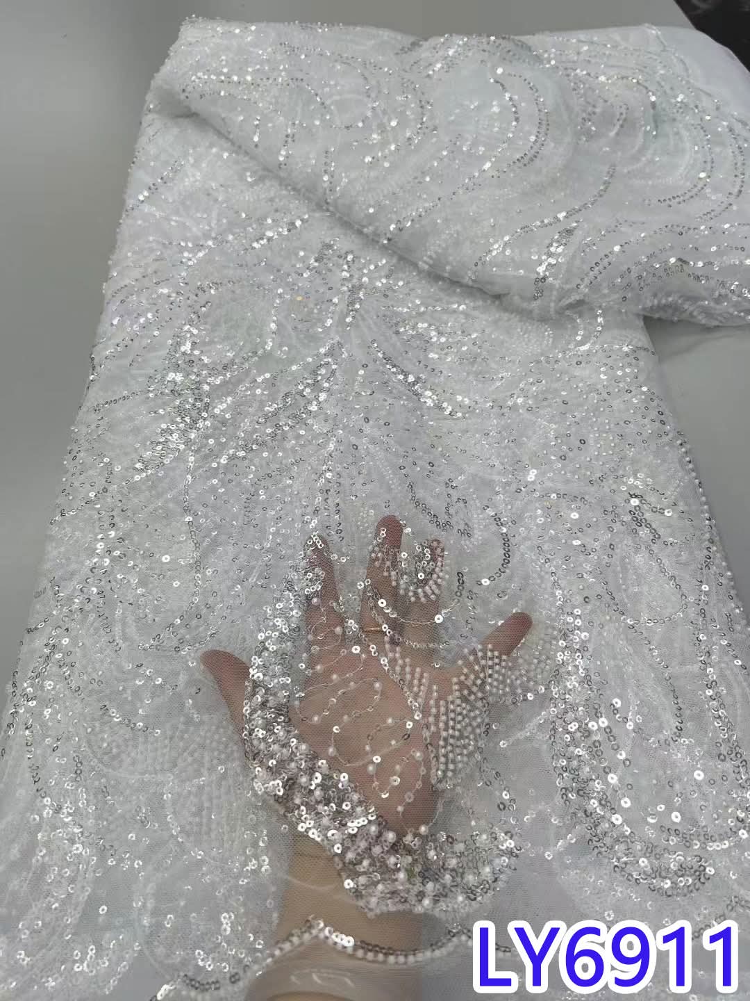 Silver sequin fabric with a hand for scale on a gray background